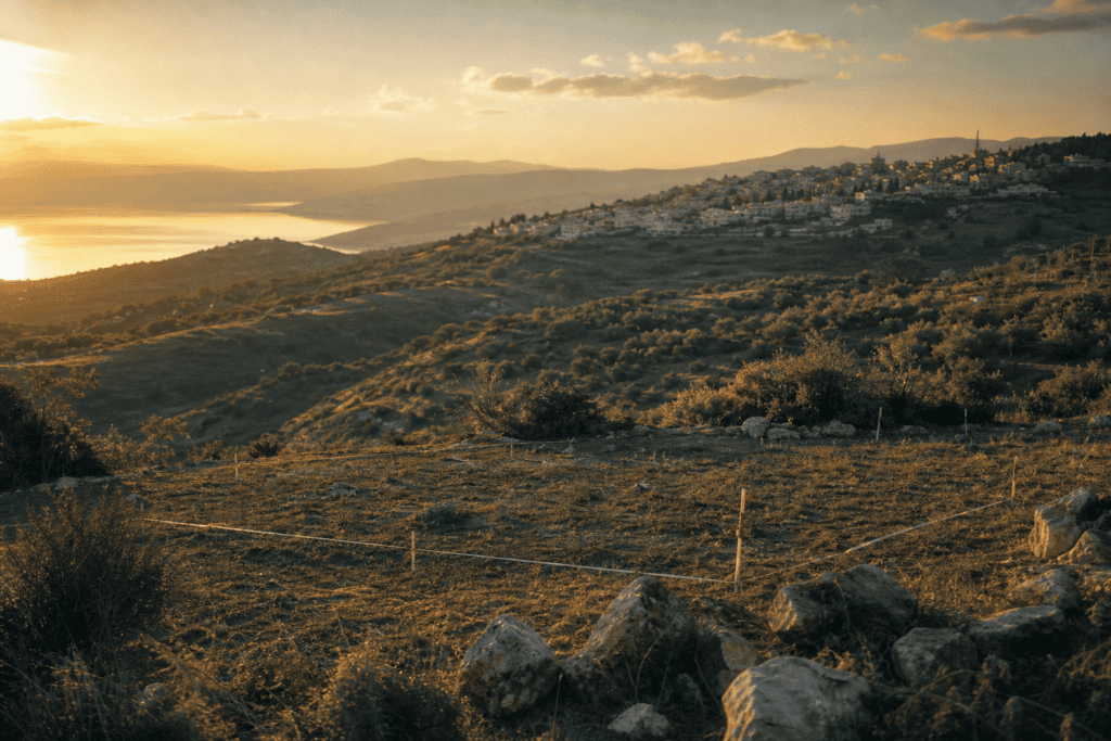 גבעות ירוקות בגליל עם מגרש פנוי לבנייה עתידית ויישוב על הרכס הסמוך